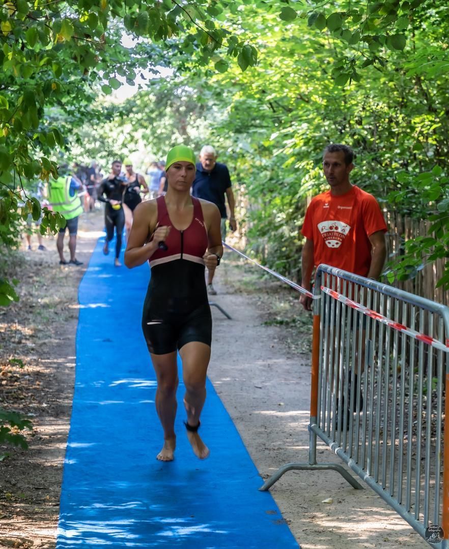 Een vrouw in een nat pak rent op een blauw pad