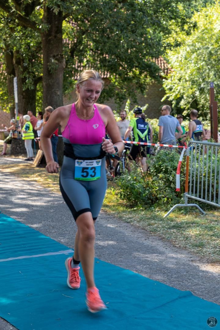 Een vrouw rent een marathon op een blauwe mat.
