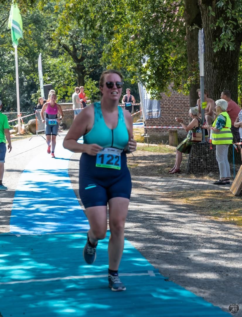 Een vrouw doet mee aan een race met nummer 122 op haar shirt.