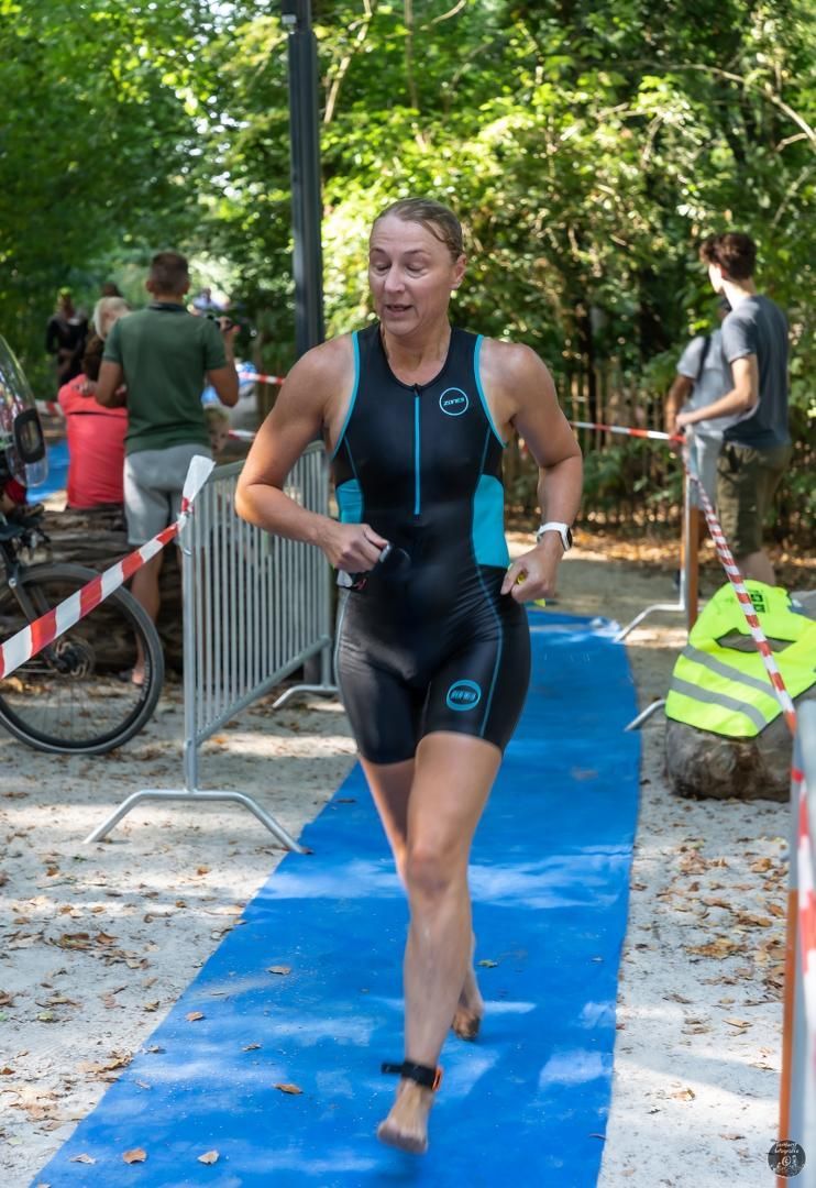 Een vrouw in een wetsuit rent op een blauwe loper.