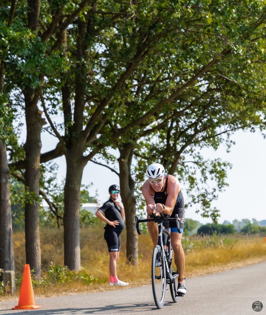 Een man fietst over een weg met bomen op de achtergrond