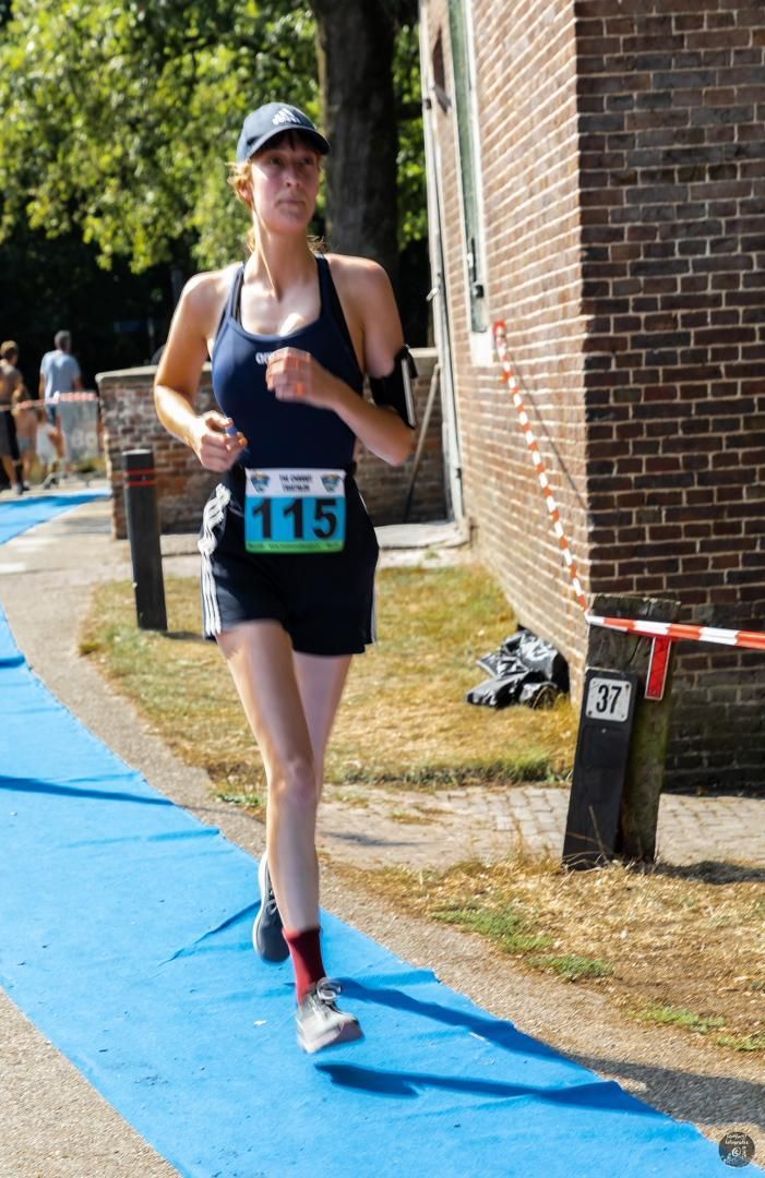 Een vrouw doet mee aan een wedstrijd met nummer 115 op haar startnummer.