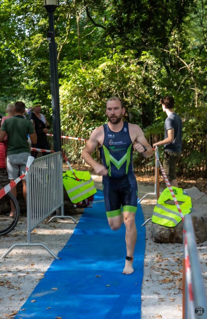 Een man rent op een blauwe loper in een park.