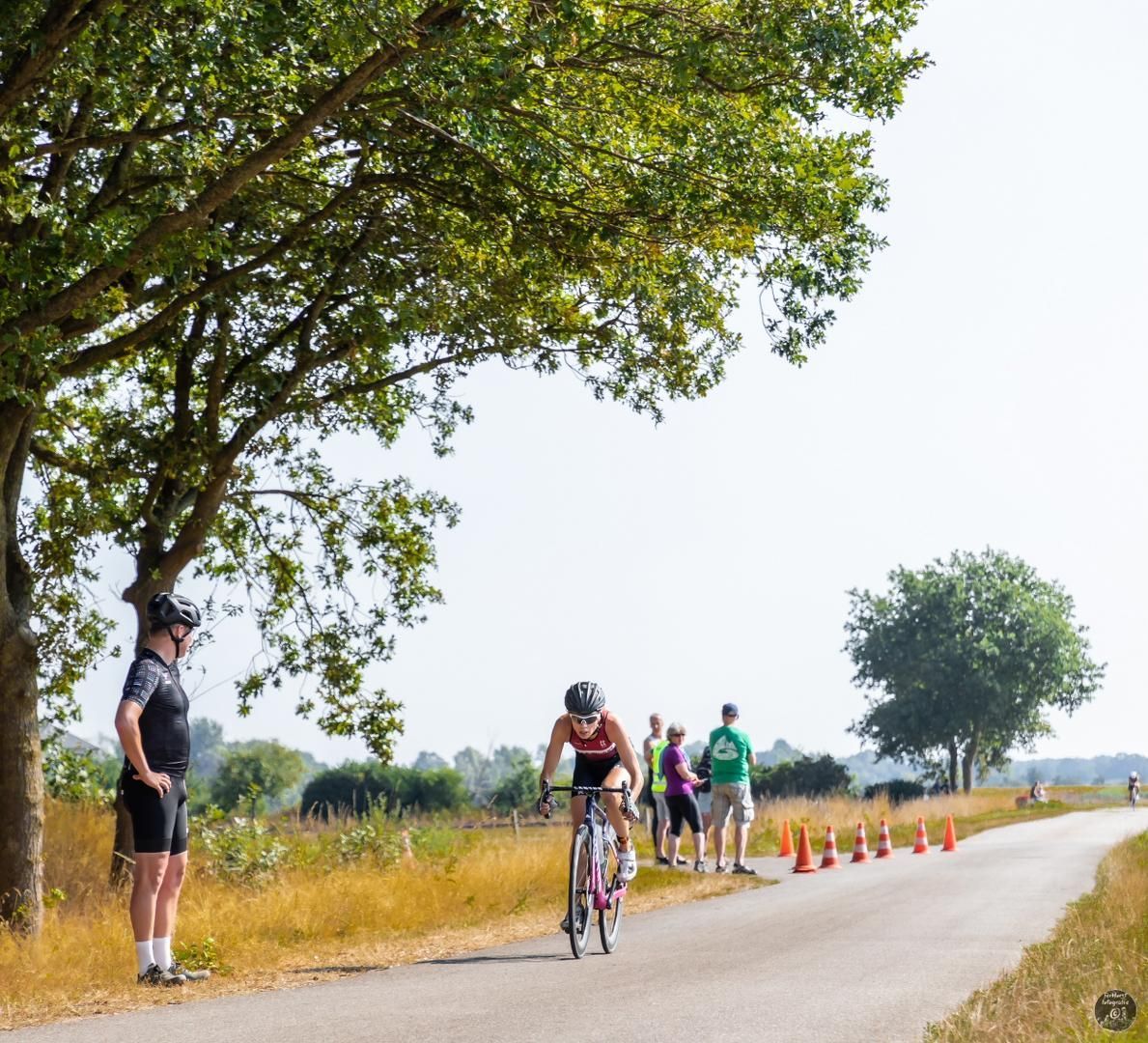 Een man fietst over een weg terwijl mensen kijken