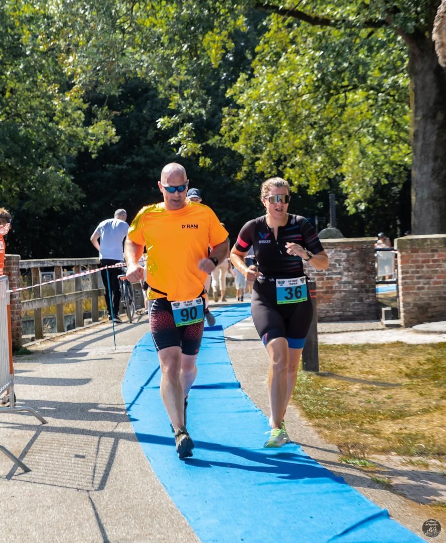 Een man en een vrouw rennen op een blauwe baan.