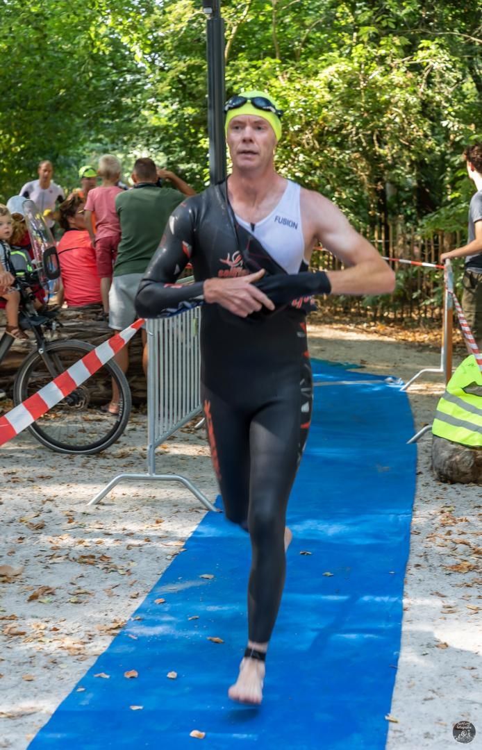 Een man in een wetsuit rent op een blauwe loper.