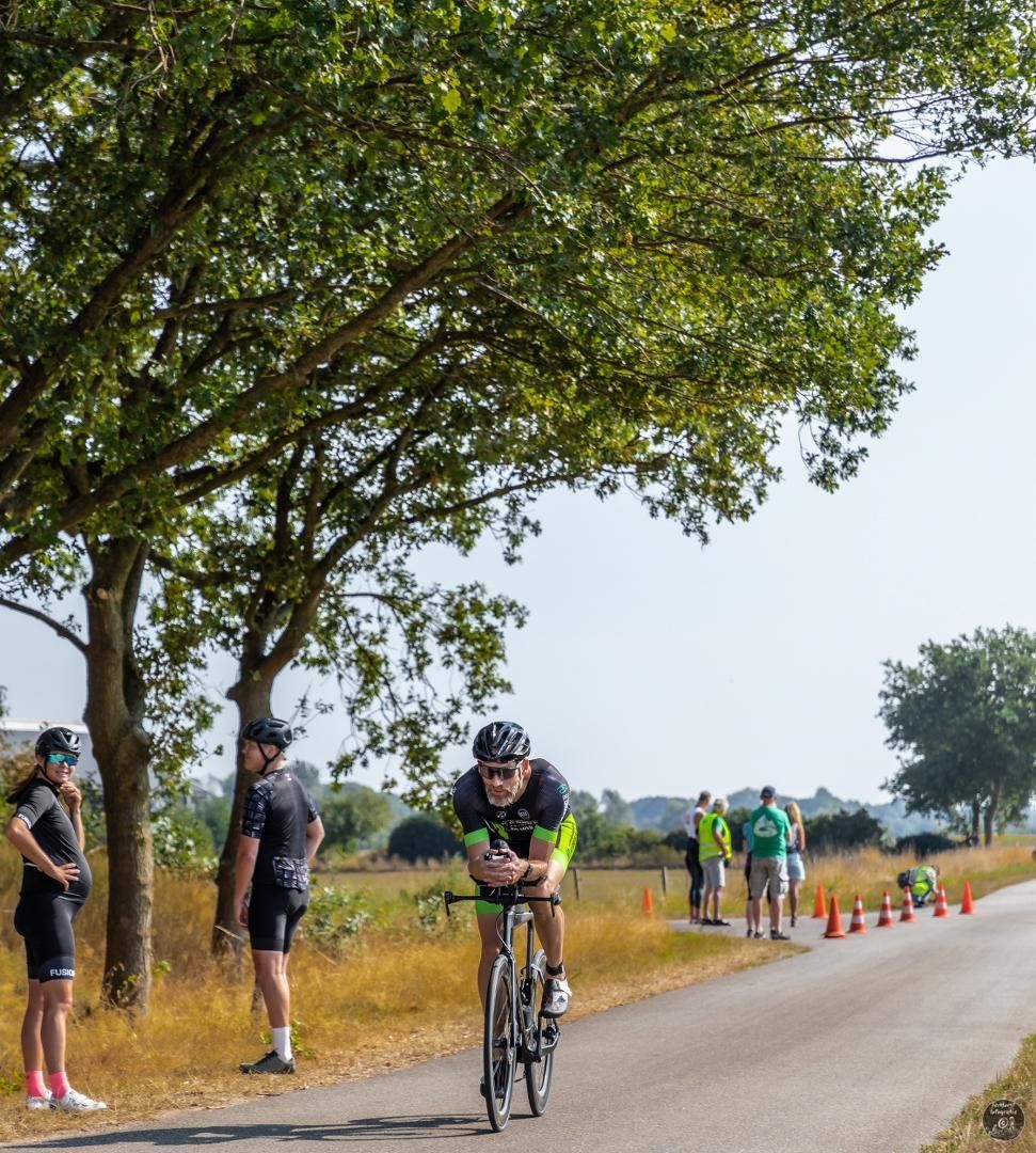 Een man fietst over een weg met bomen op de achtergrond