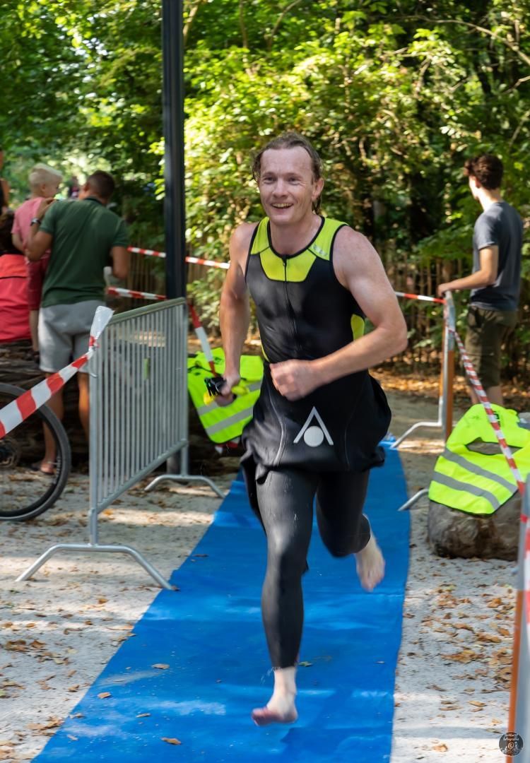 Een man in een wetsuit rent op een blauwe mat