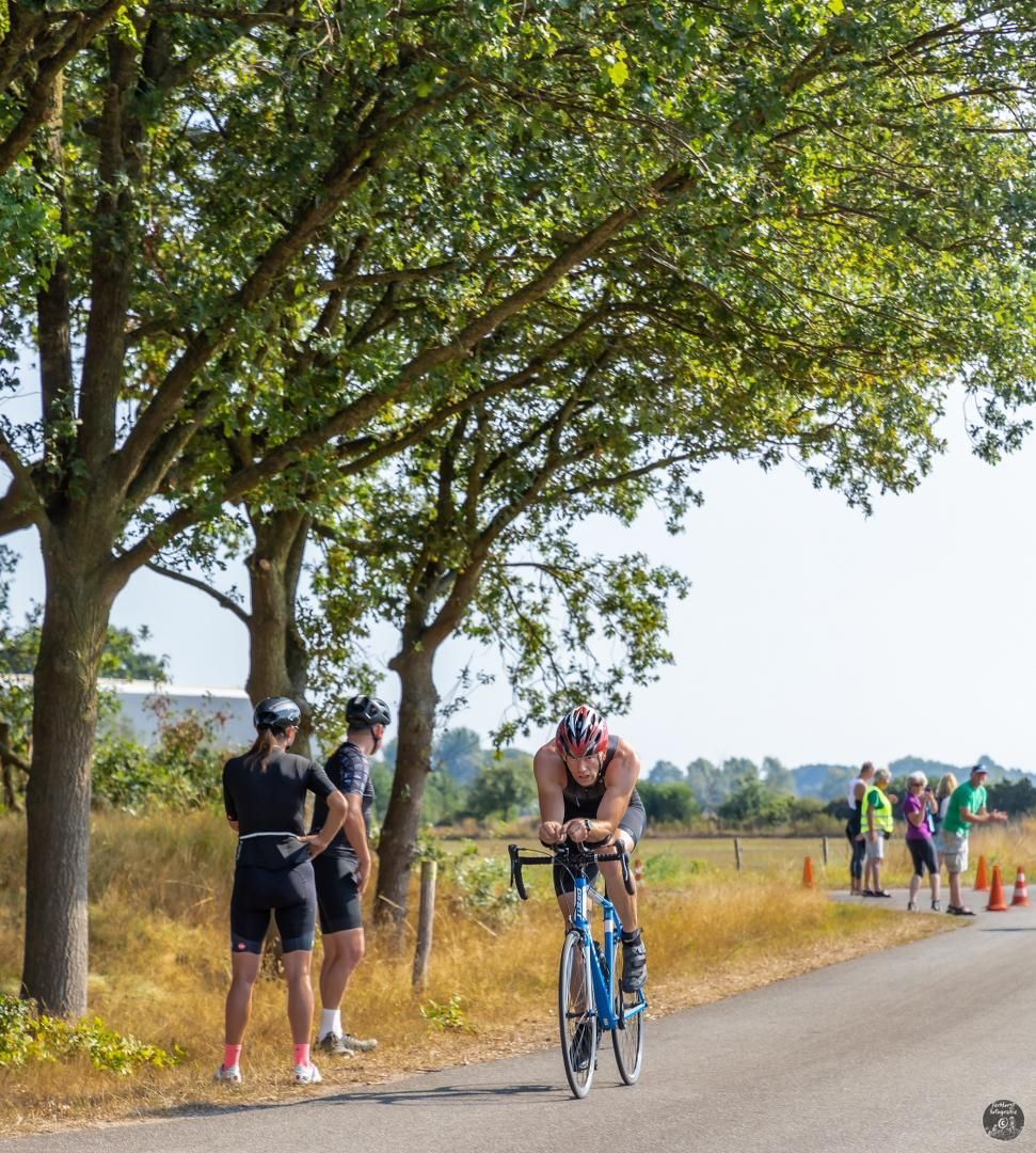 Een man fietst over een weg langs bomen.