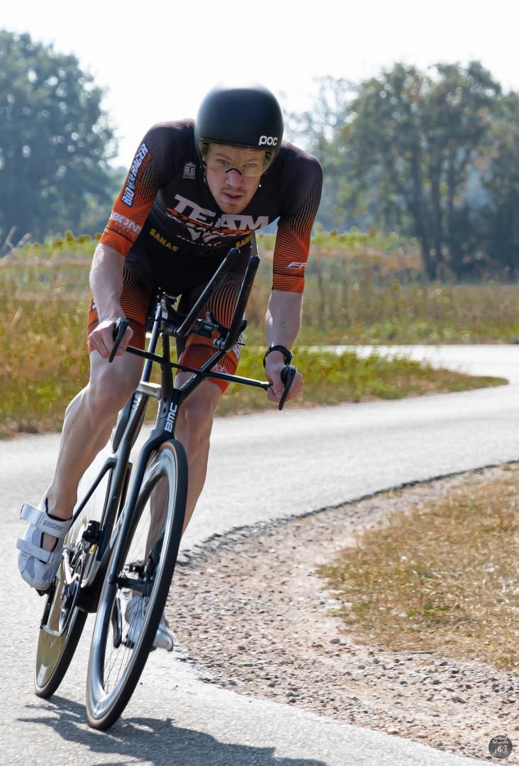 Een man met een helm rijdt op een fiets over de weg.