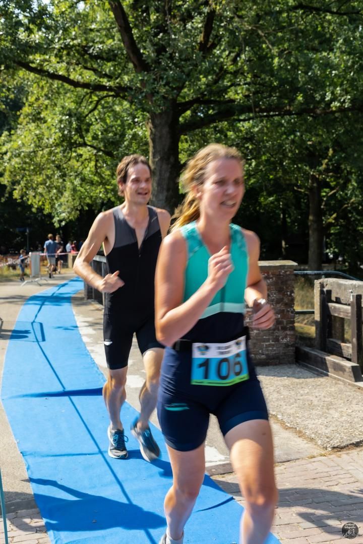 Een man en een vrouw rennen op een blauwe baan.