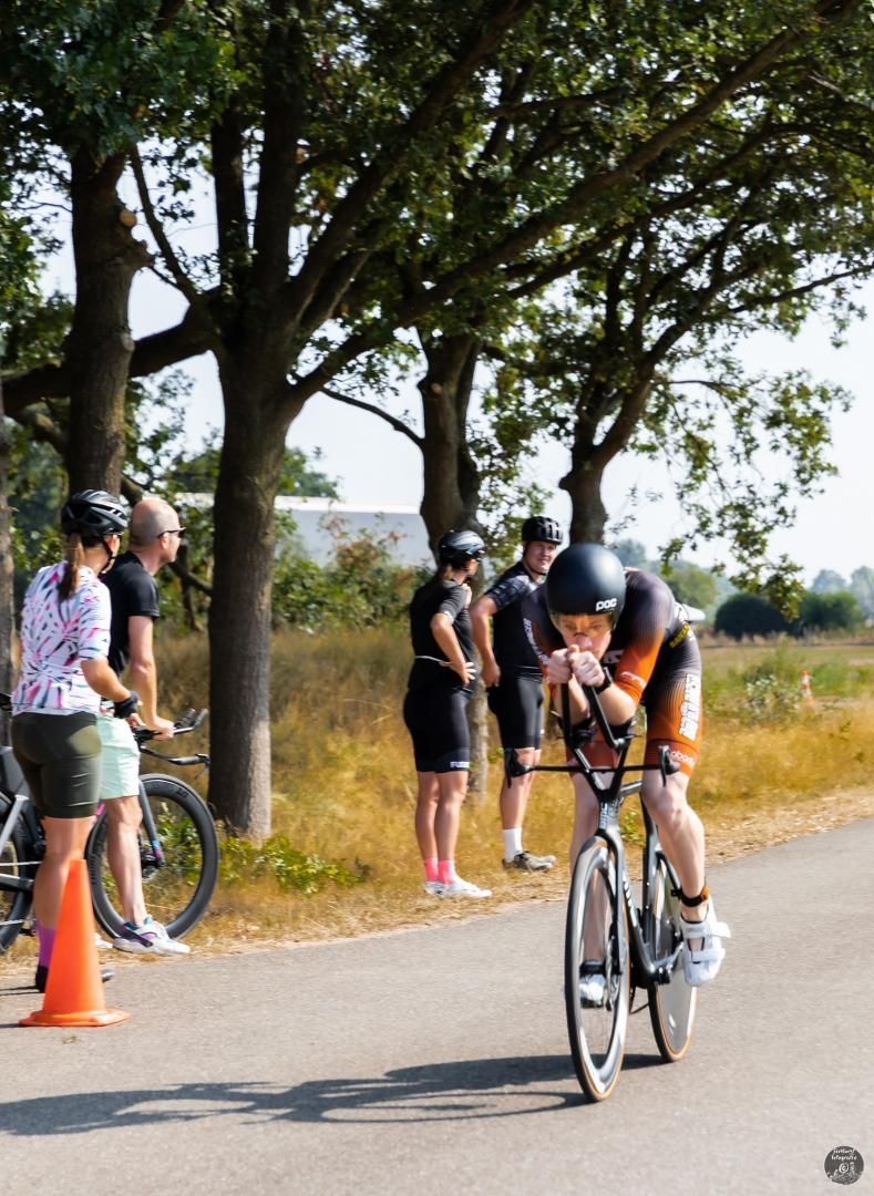 Een man fietst over een weg terwijl mensen kijken