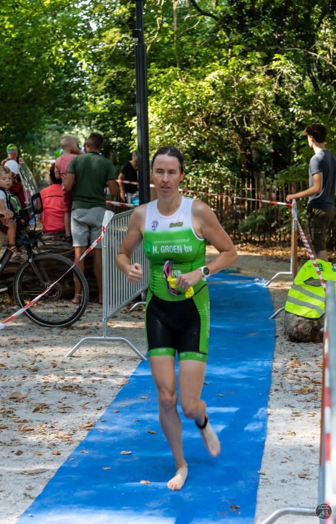 Een vrouw rent op een blauwe mat tijdens een triatlon.