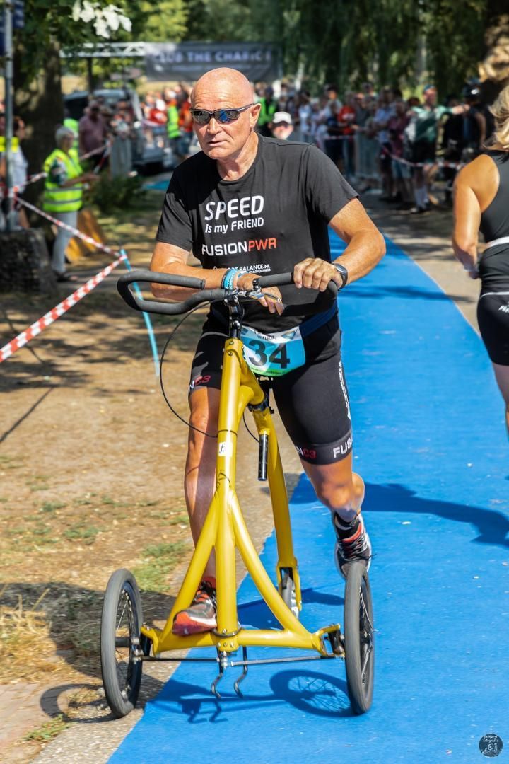 Een man rijdt op een gele fiets op een blauwe loper.