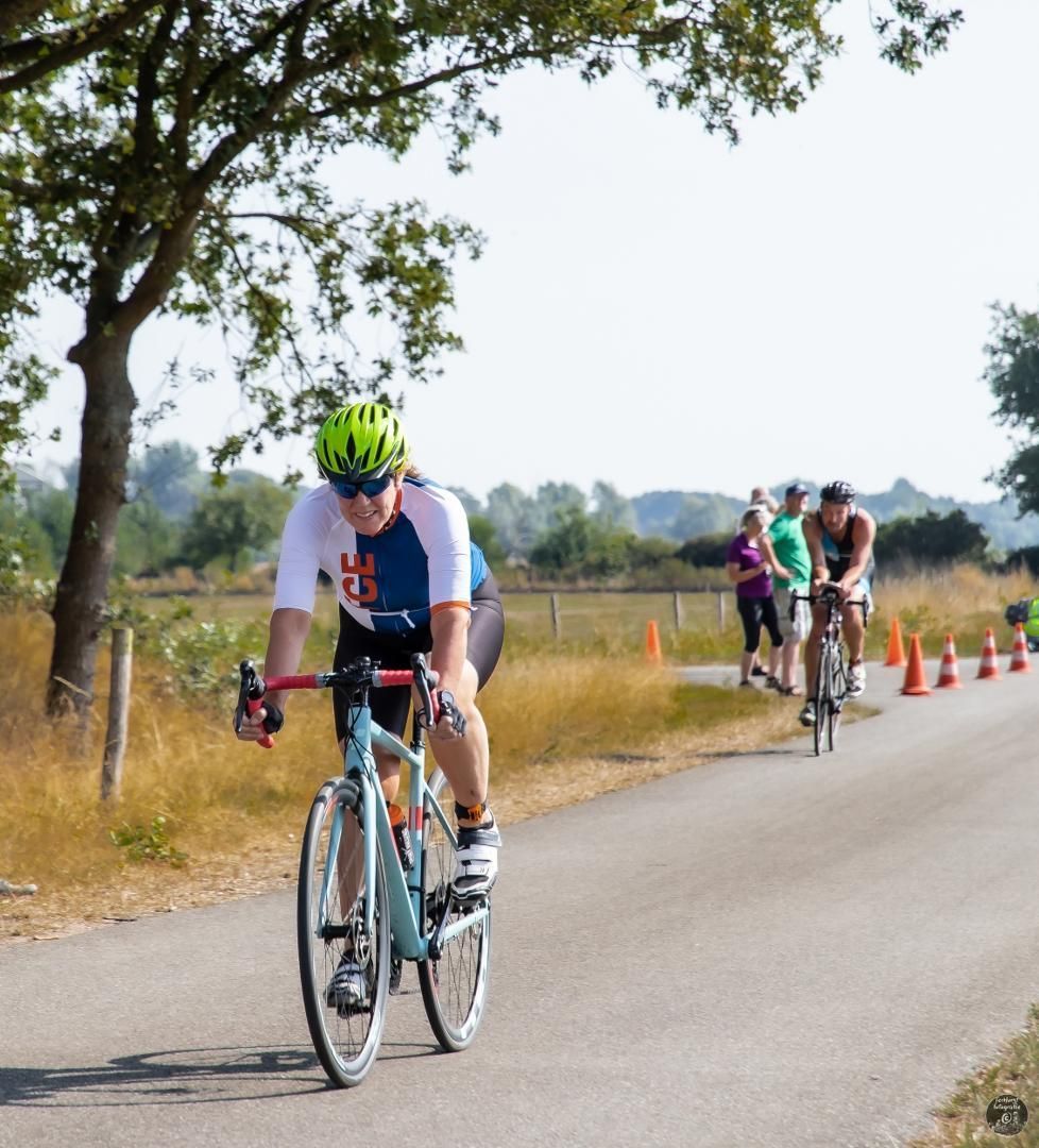 Een man met een helm rijdt op een fiets over een weg