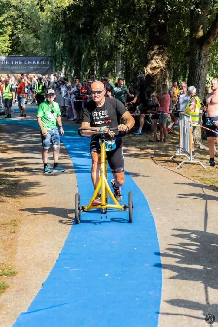 Een man rijdt op een gele scooter op een blauw pad.
