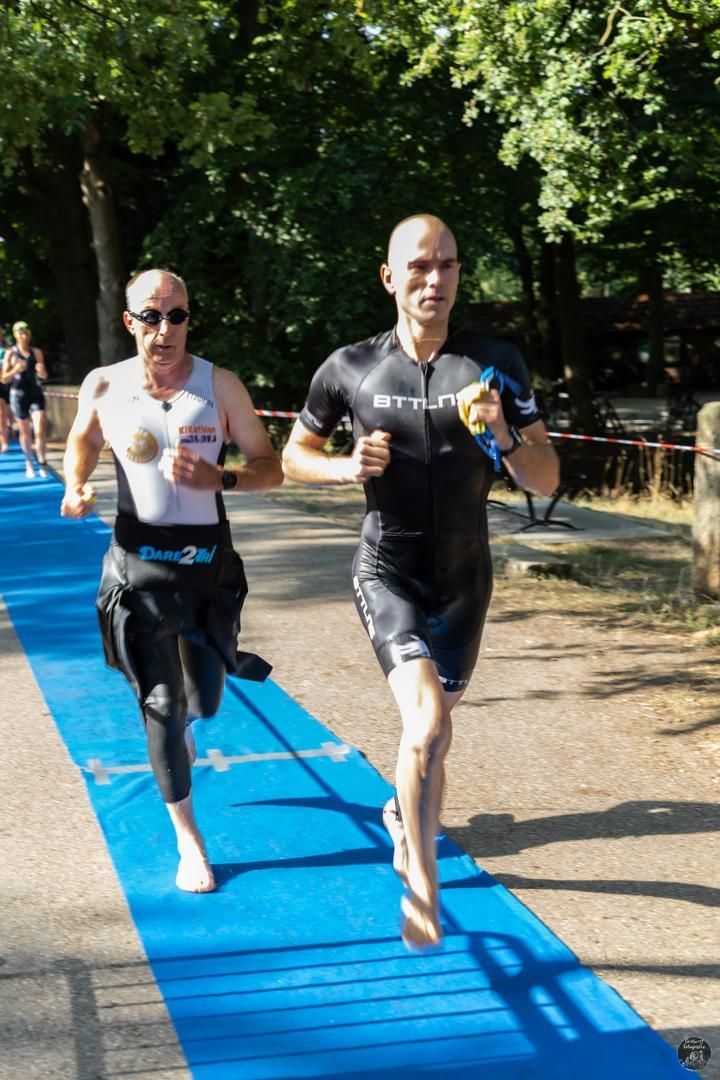 Twee mannen rennen over een blauwe loper.