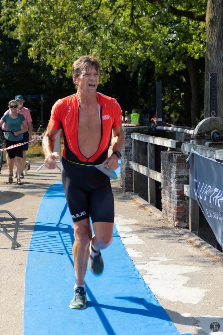 Een man in een rood shirt rent over een blauwe loper.