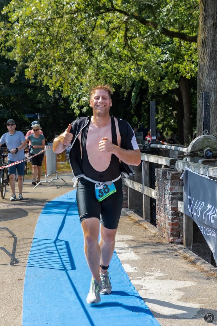 Een man rent op een blauwe loper in een park.