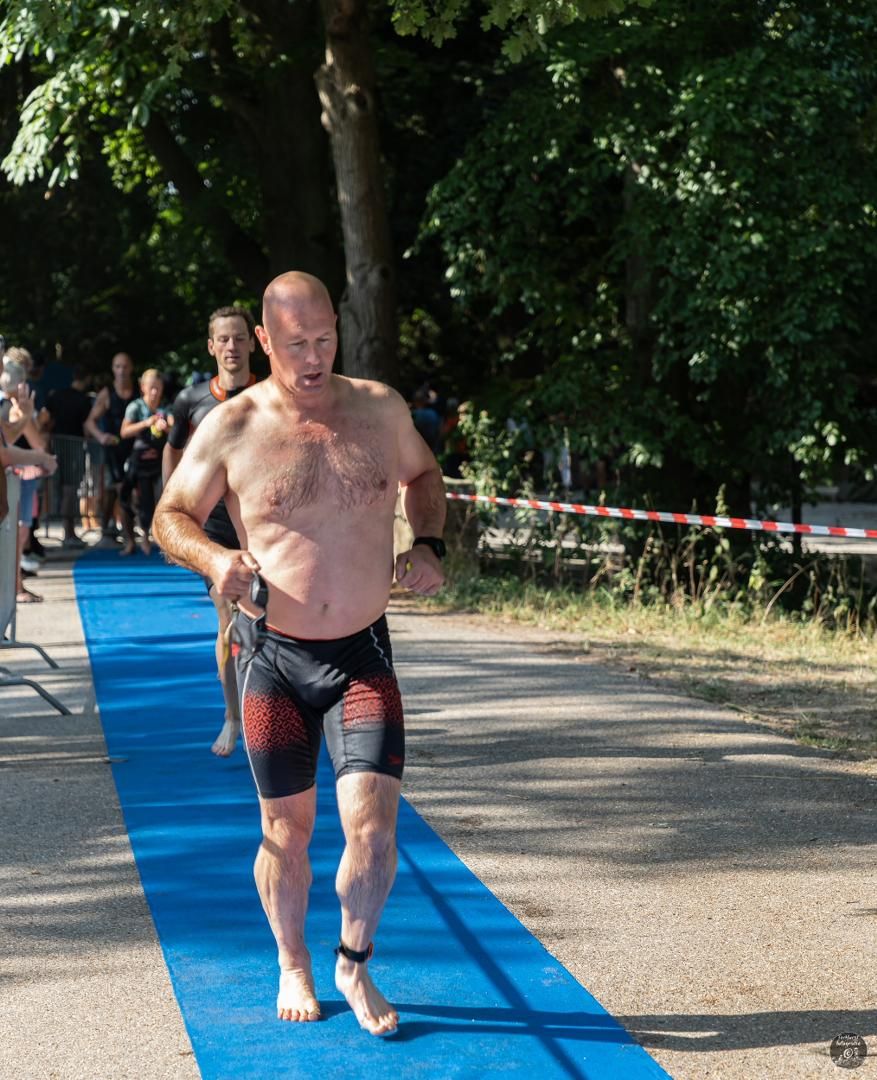 Een man zonder shirt rent over een blauwe loper