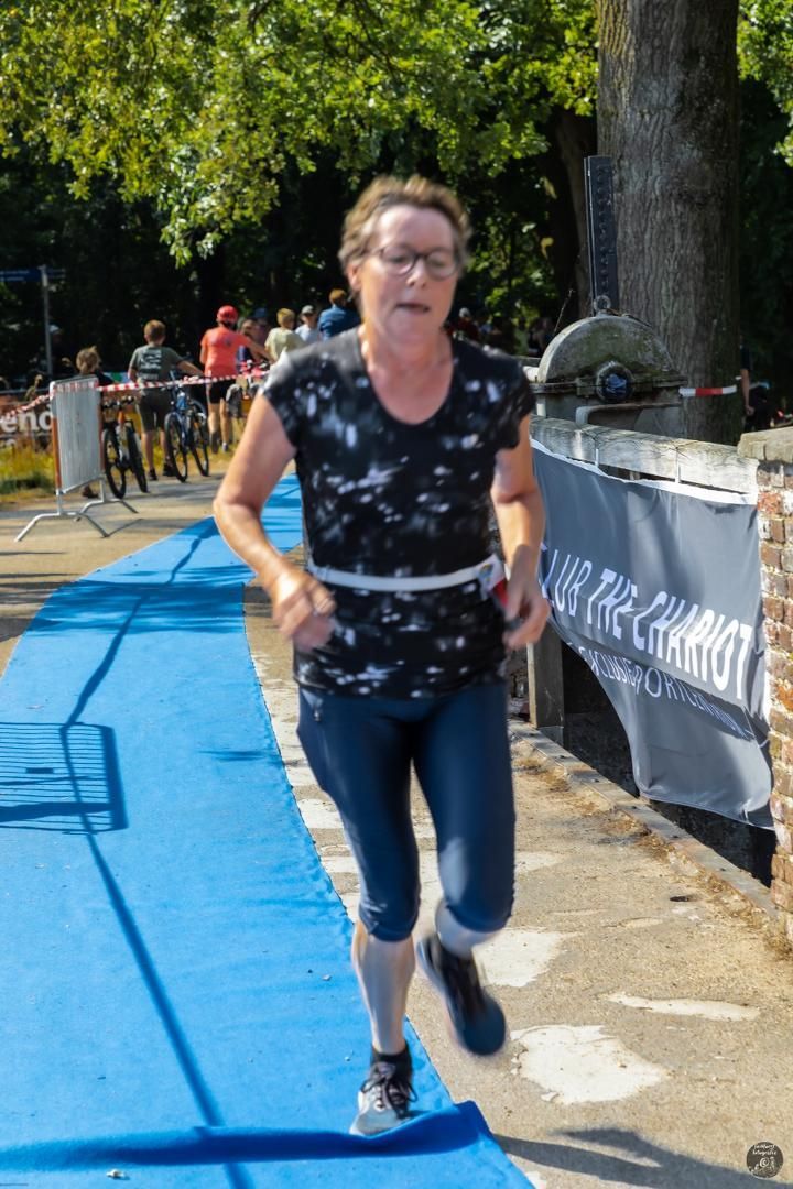 Een vrouw rent op een blauwe baan in een park.