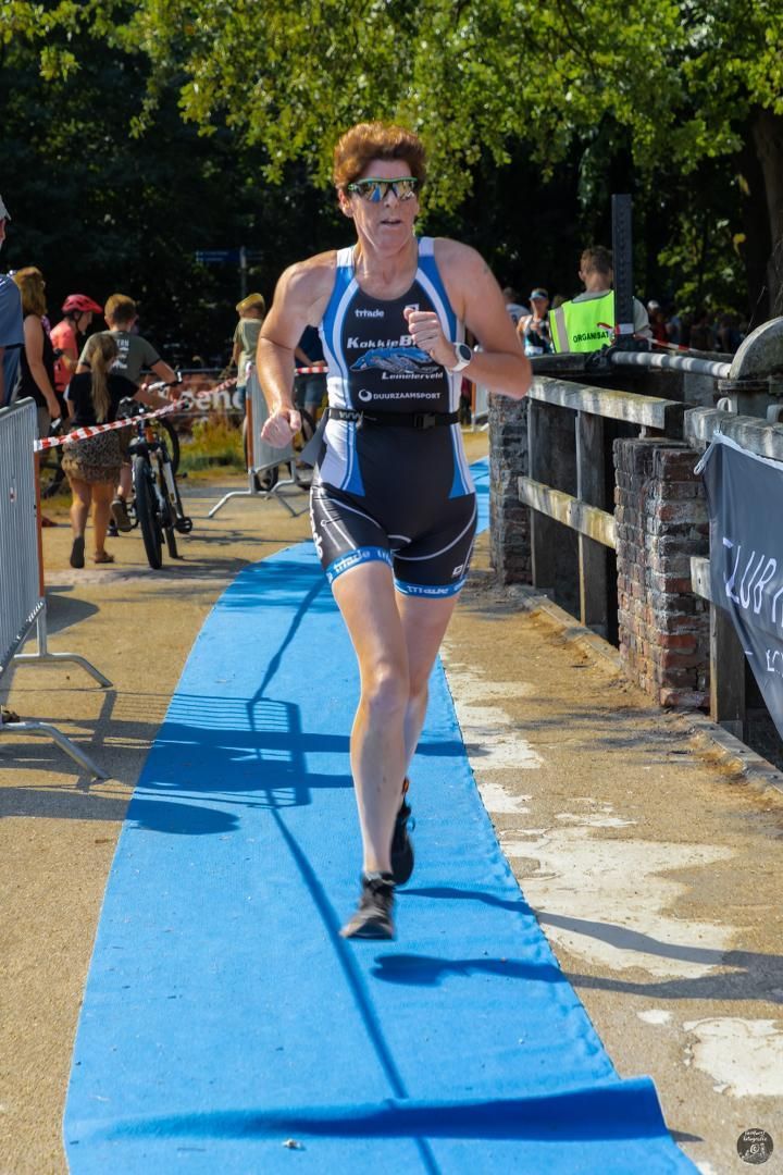 Een vrouw rent op een blauwe loper tijdens een triatlon.
