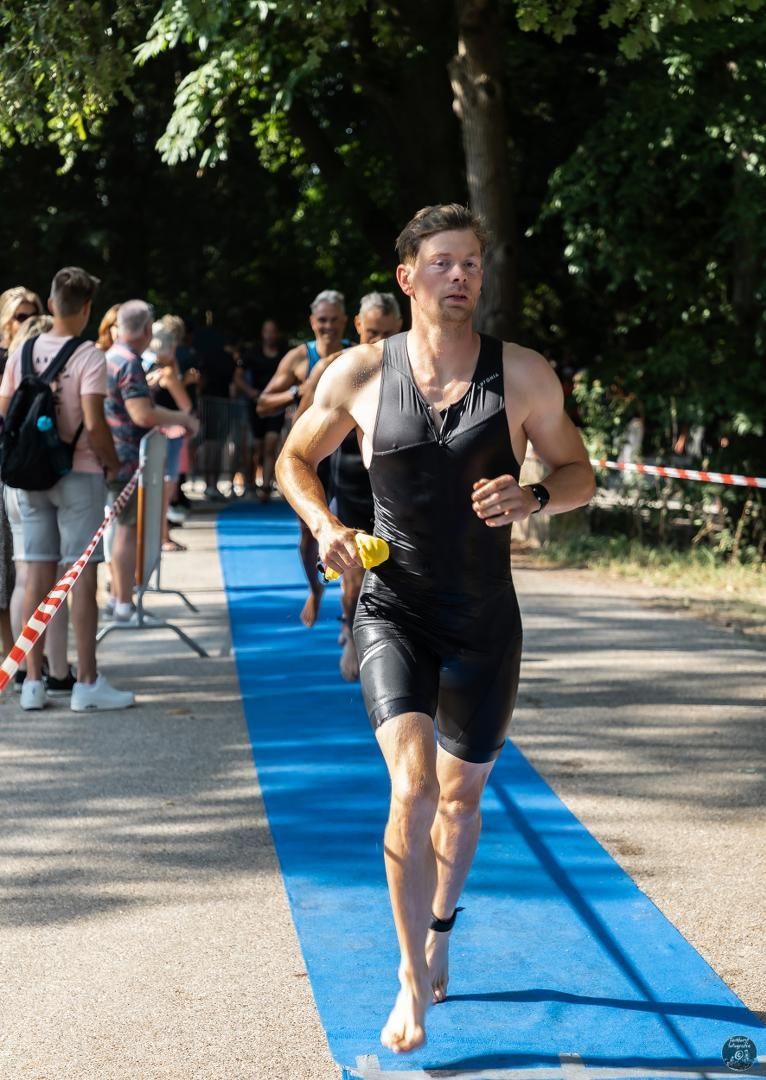 Een man in een nat pak rent op een blauwe loper