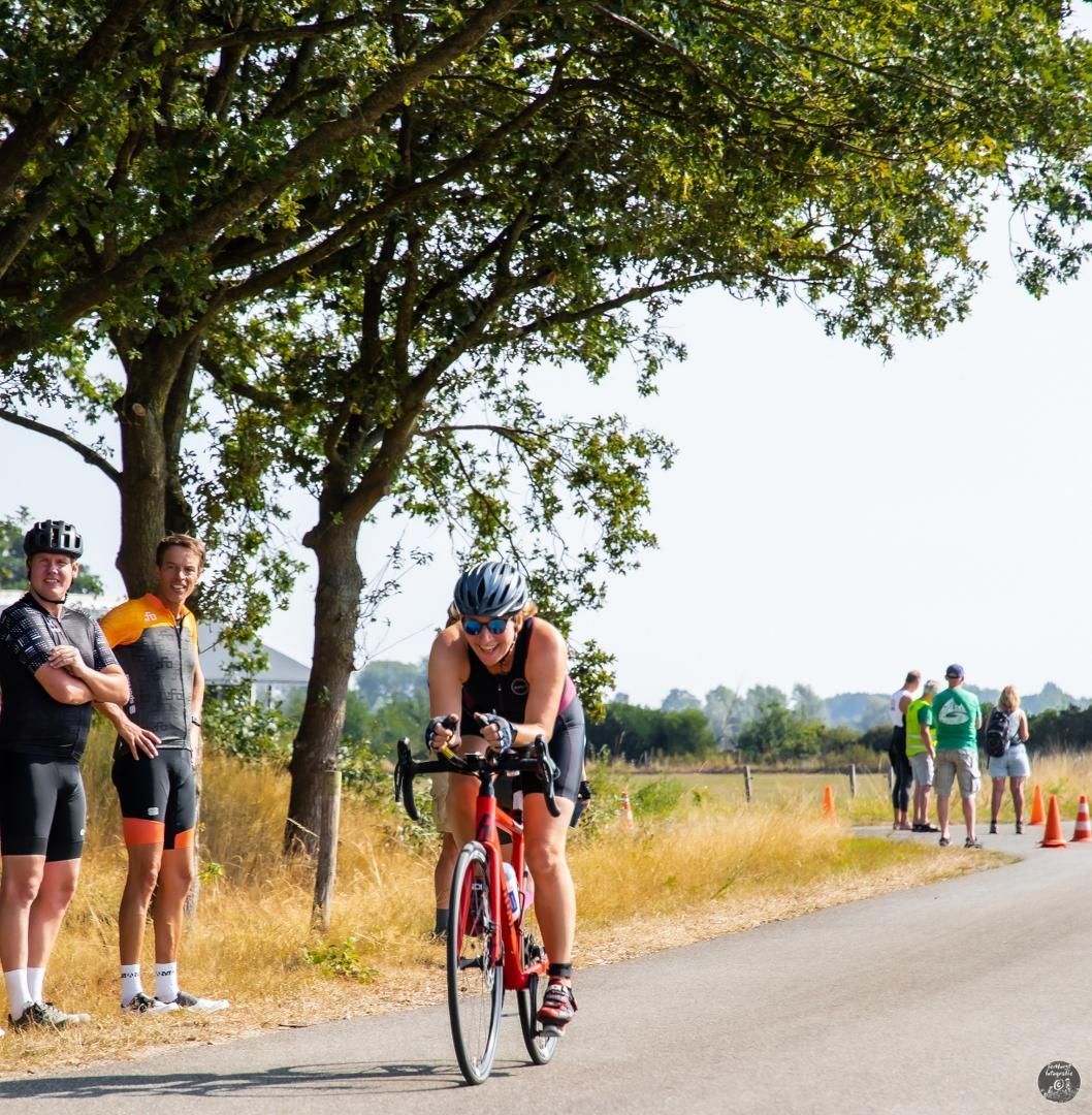 Een vrouw fietst over een weg terwijl mensen toekijken