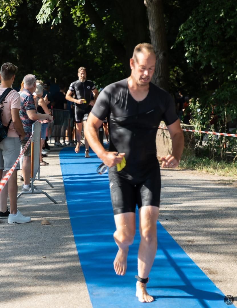 Een man in een zwart shirt rent op een blauwe mat