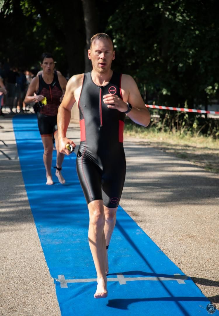 Een man in een zwart pak rent op een blauwe mat