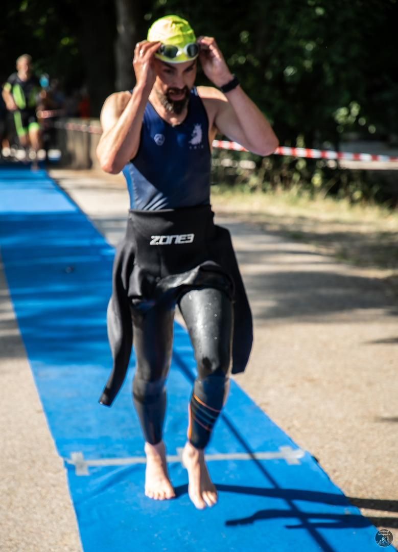 Een man in een wetsuit loopt op een blauwe mat