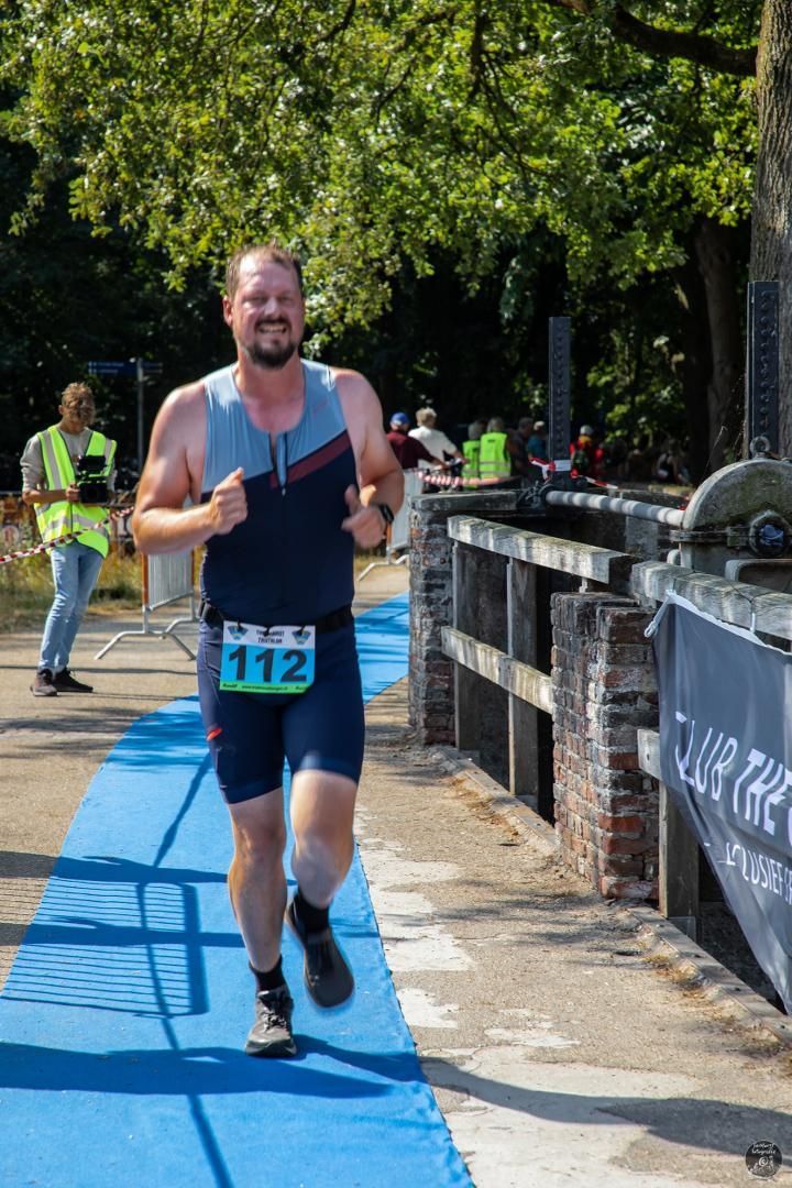 Een man rent op een blauwe baan in een park.