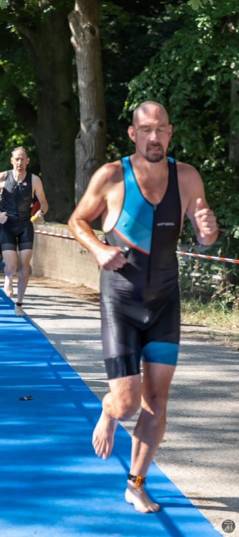 Een man rent op een blauwe mat tijdens een triatlon.