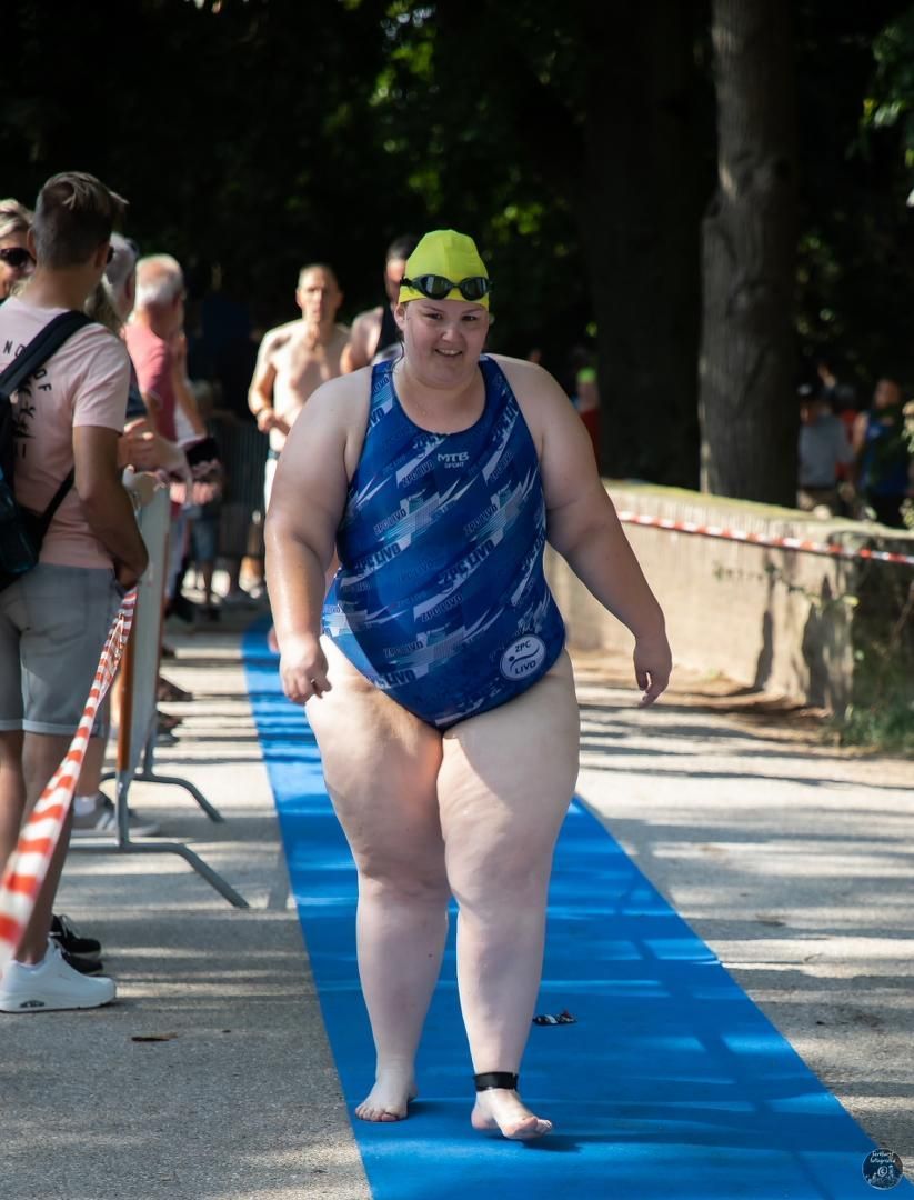 Een vrouw in een blauw badpak loopt op een blauw tapijt