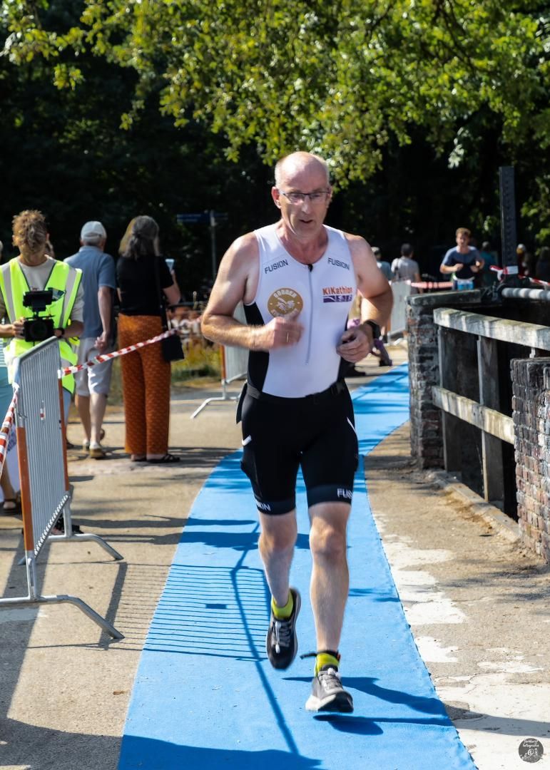 Een man rent over een blauwe loper met een paar mensen die toekijken