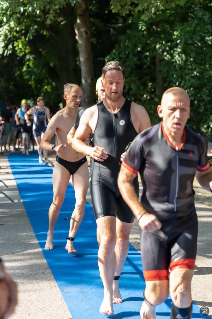 Een groep mannen rent over een blauwe loper.