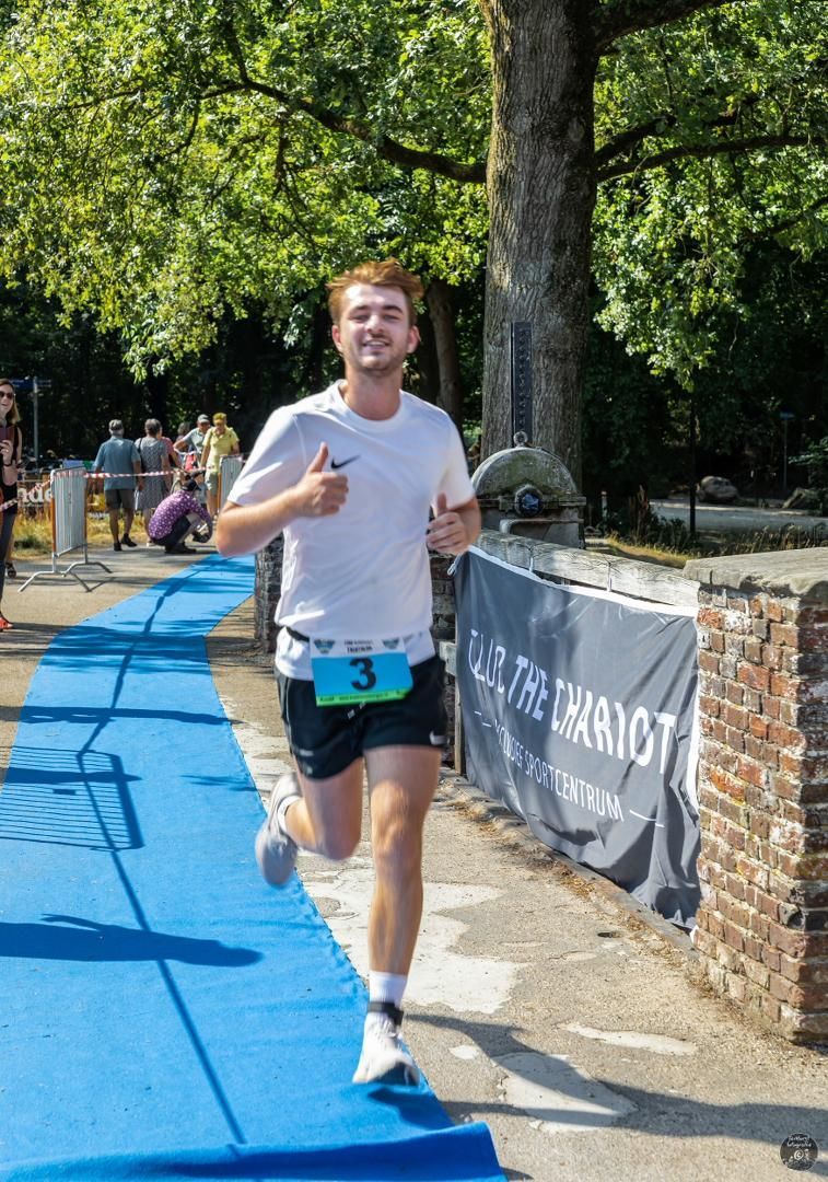 Een man met startnummer 3 rent op een blauwe baan.