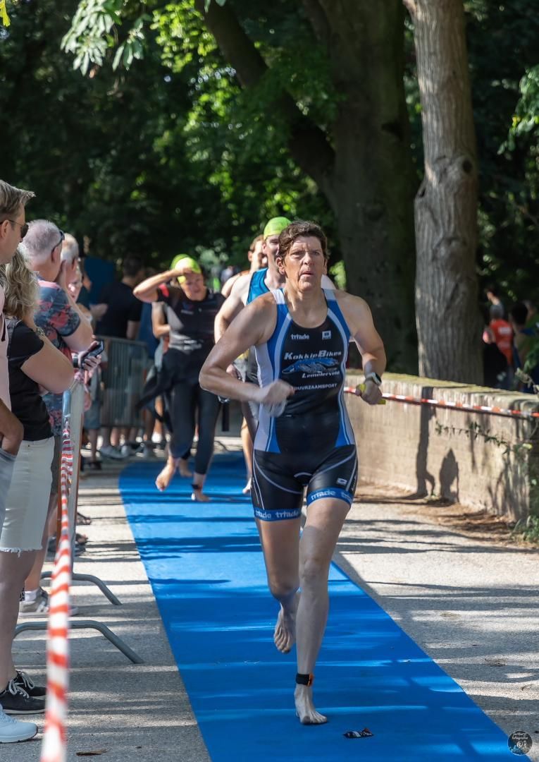 Een vrouw rent over een blauwe loper voor een menigte.