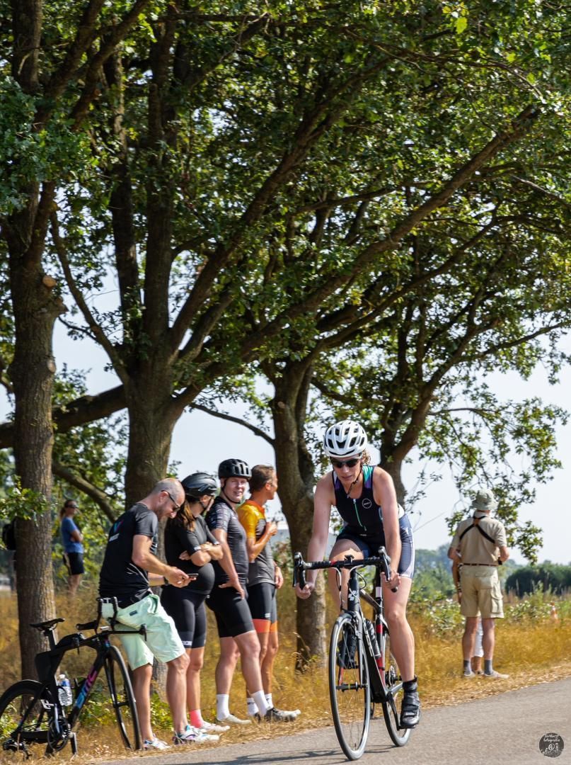 Een man fietst over een weg terwijl een groep mensen toekijkt.
