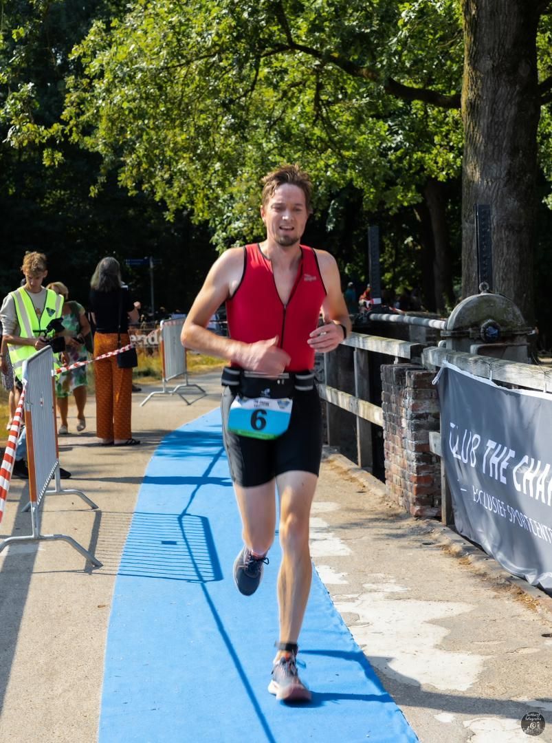 Een man die op een blauwe loper rent met het nummer 6 op zijn riem