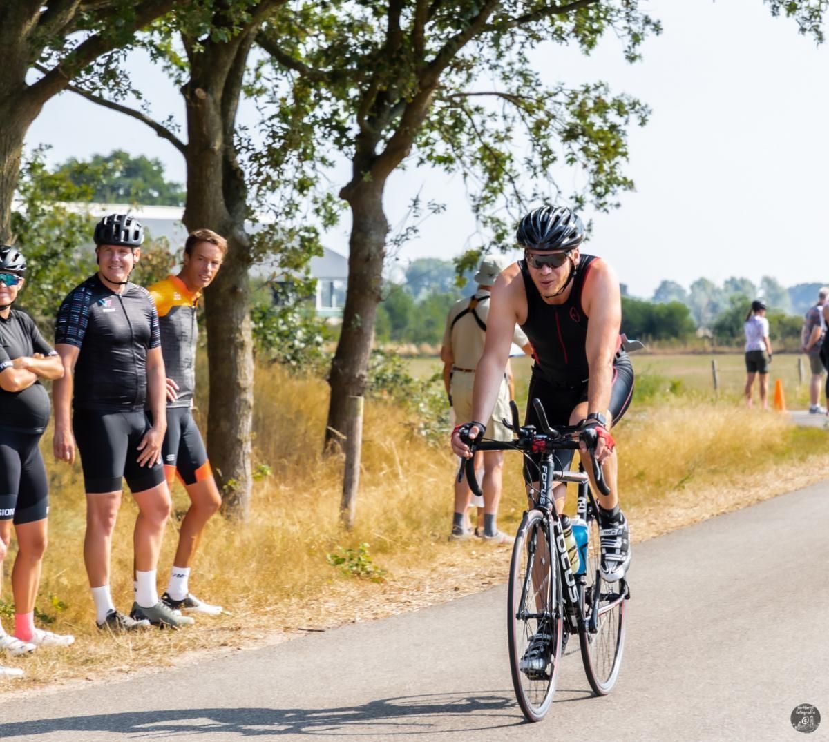 Een man met een helm rijdt op een fiets over een weg