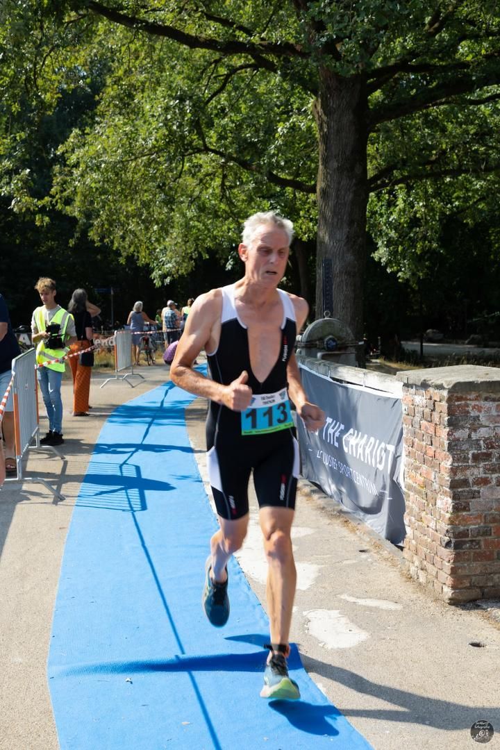 Een man in een triatlonpak rent op een blauwe baan.