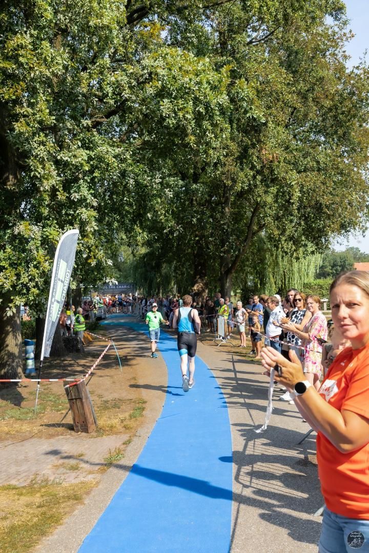 Een vrouw in een oranje shirt staat naast een blauw pad.