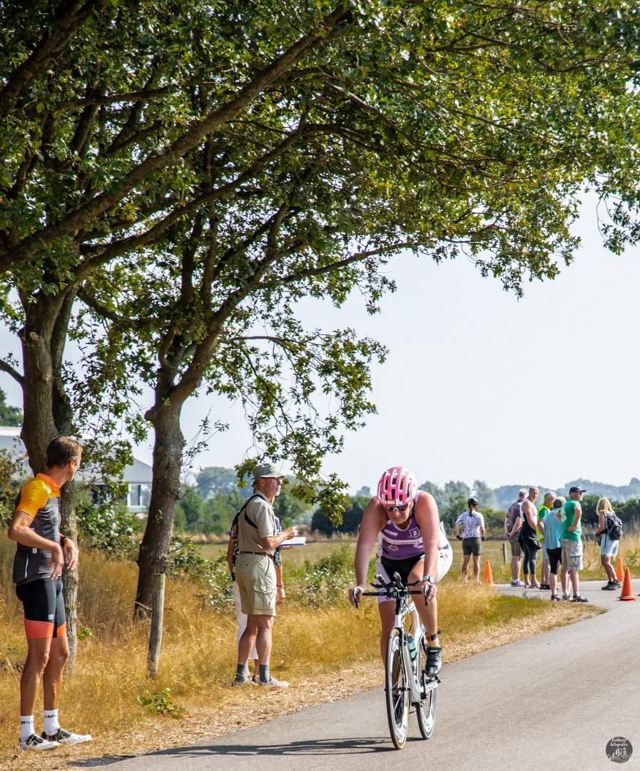 Een vrouw fietst over een weg terwijl mensen toekijken.
