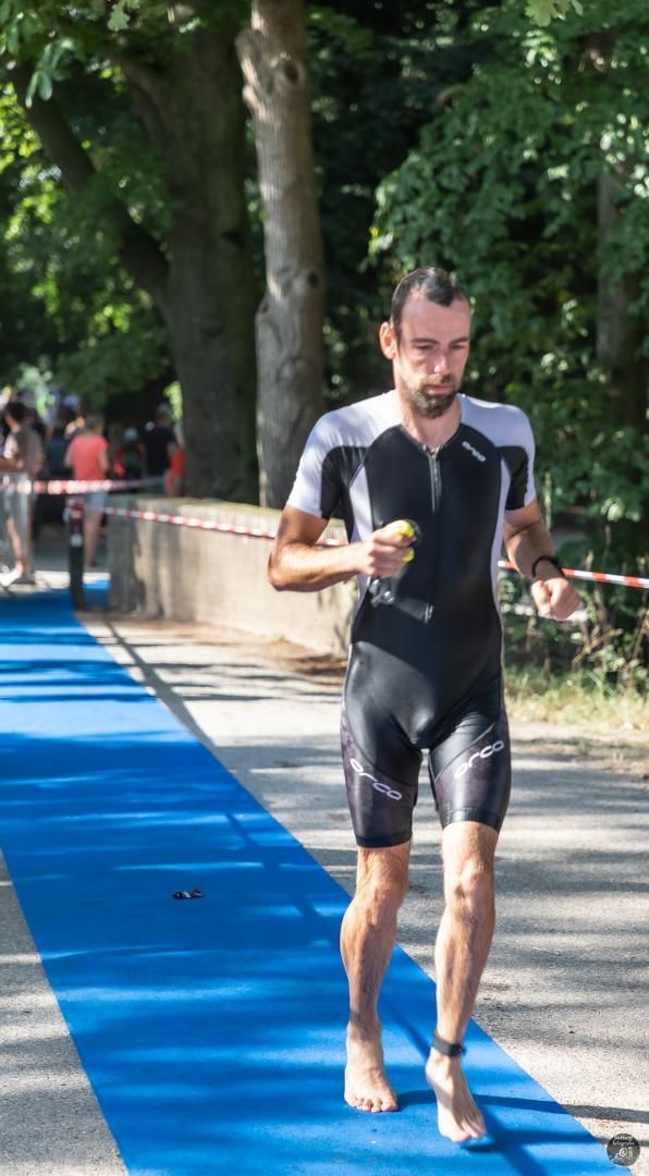 Een man in een wetsuit loopt op een blauwe mat.