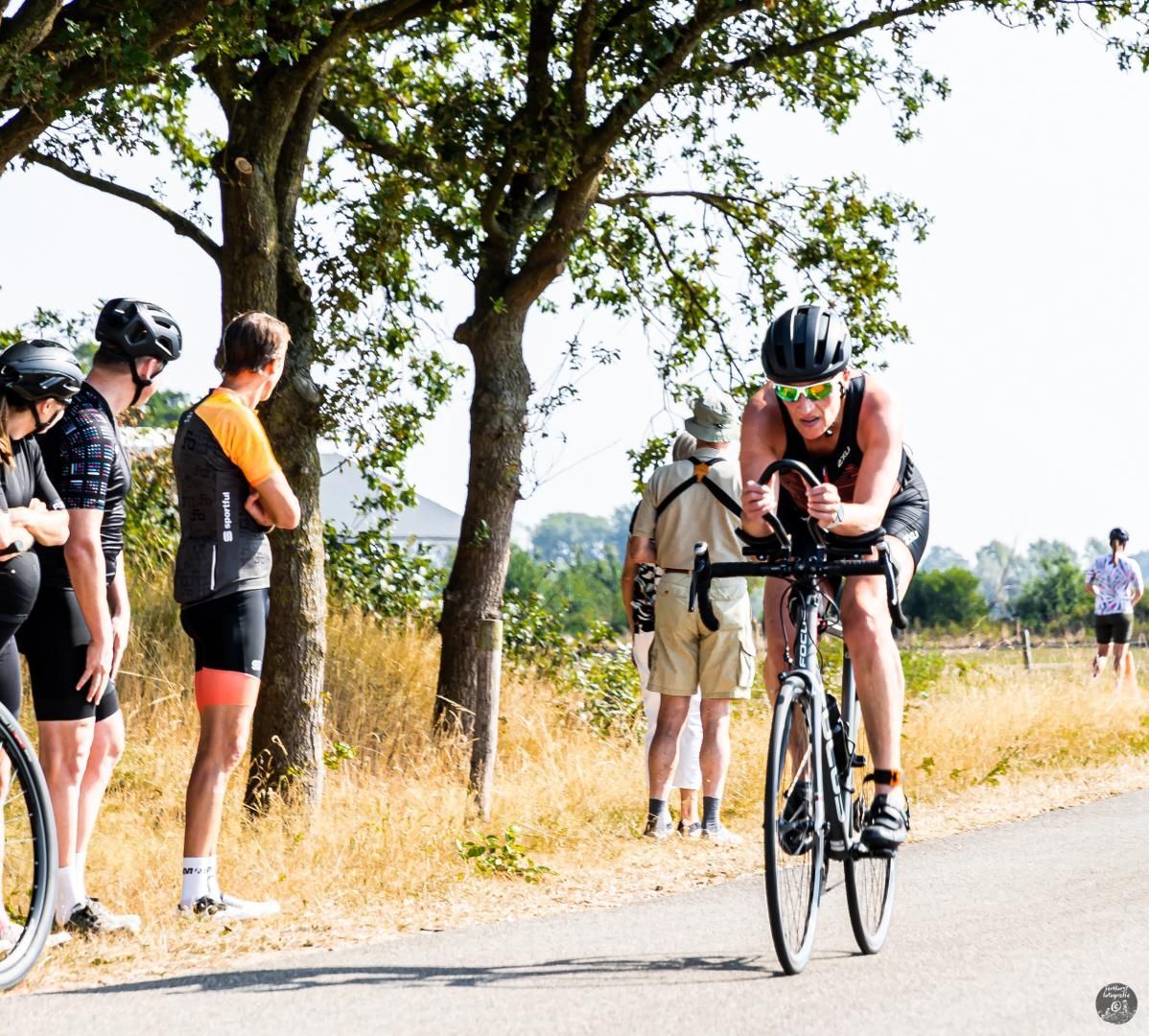 Een vrouw fietst over een weg terwijl mensen toekijken