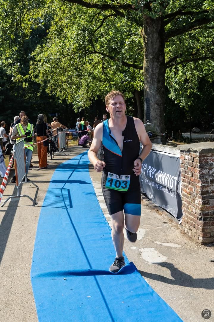 Een man rent op een blauwe baan tijdens een triatlon.