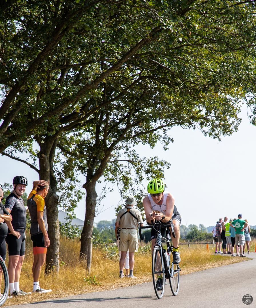 Een man met een helm rijdt op een fiets over de weg.