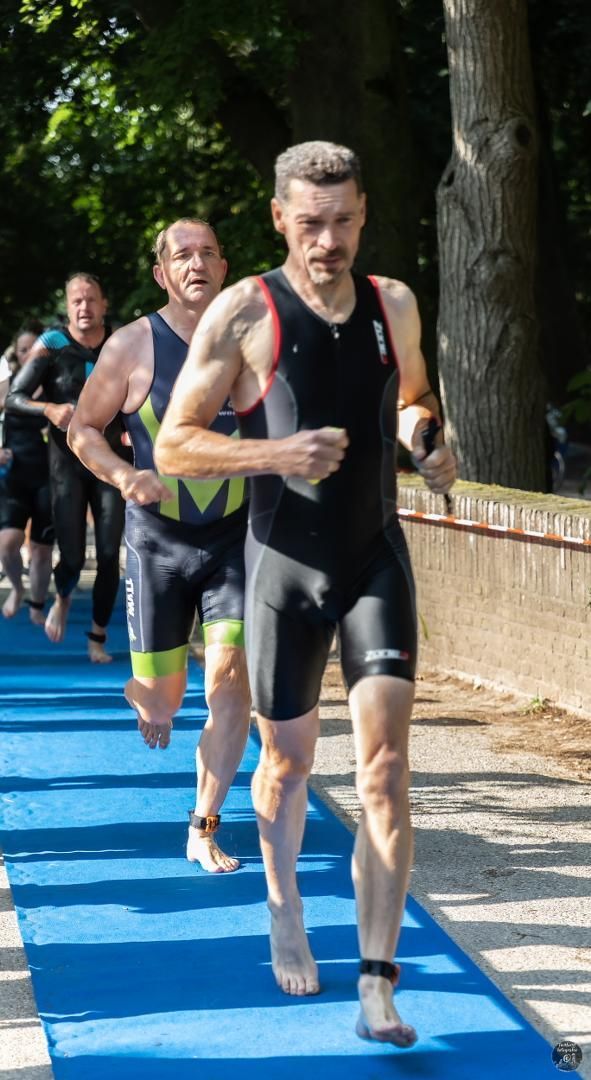 Een groep mannen rent een triatlon op een blauwe mat.