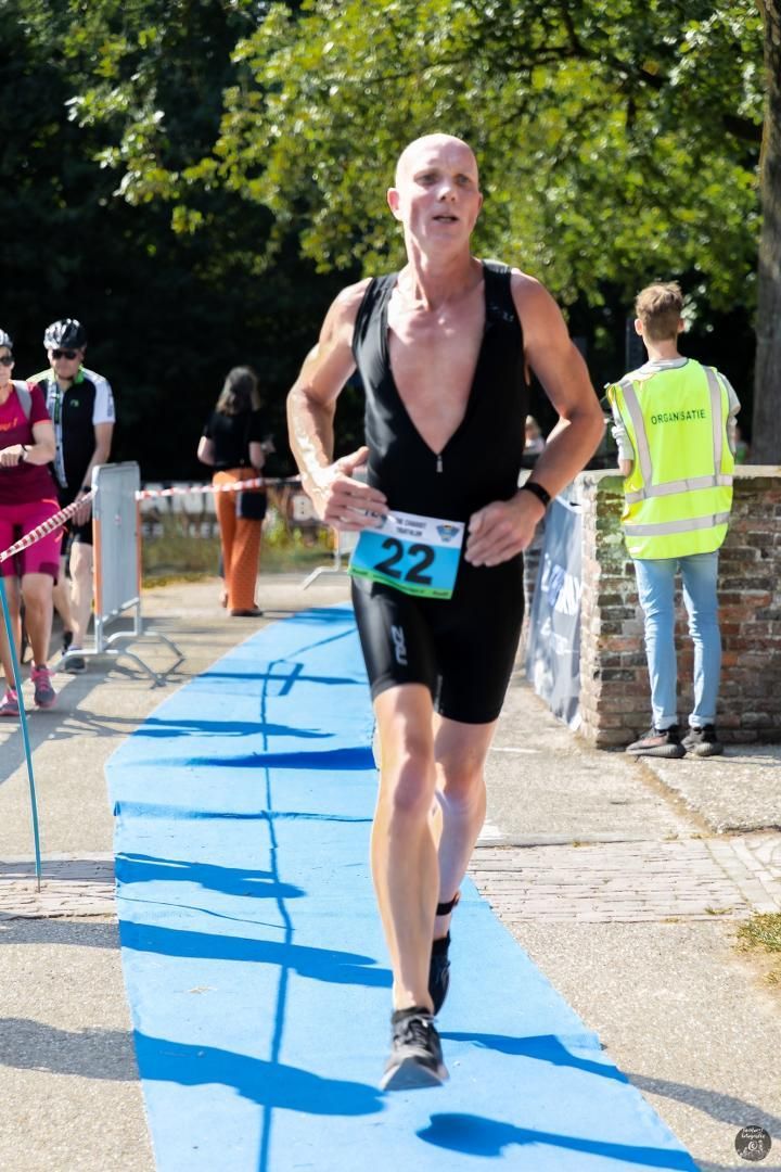Een man rent mee in een triatlon met nummer 22 op zijn startnummer.